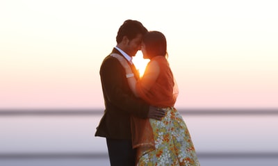 男人身穿黑色背心亲吻女人穿着白色红色和绿色的连衣裙
